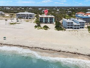 Un hôtel situé en bord de mer, composé de plusieurs bâtiments, avec une plage de sable et des vagues de l’océan.