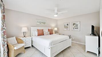 A bedroom with a bed, two bedside tables, a chair, a desk, and a ceiling fan.