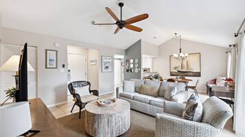 A modern living room with a sofa, armchairs, a coffee table, and a ceiling fan.