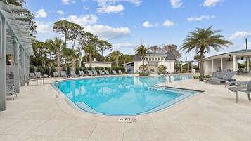 A swimming pool with lounge chairs and a building in the background.