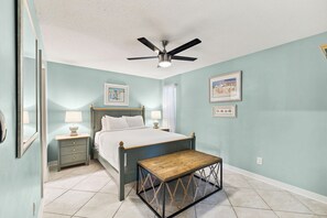 Ein Schlafzimmer mit einem Bett, Nachttischen, einem Deckenventilator und Bildern an den Wänden.