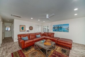 Ein Wohnzimmer mit Ecksofa, Couchtisch und Deckenventilator.