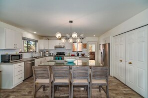A modern kitchen with white cabinets, a central island, and a dining area with four chairs.