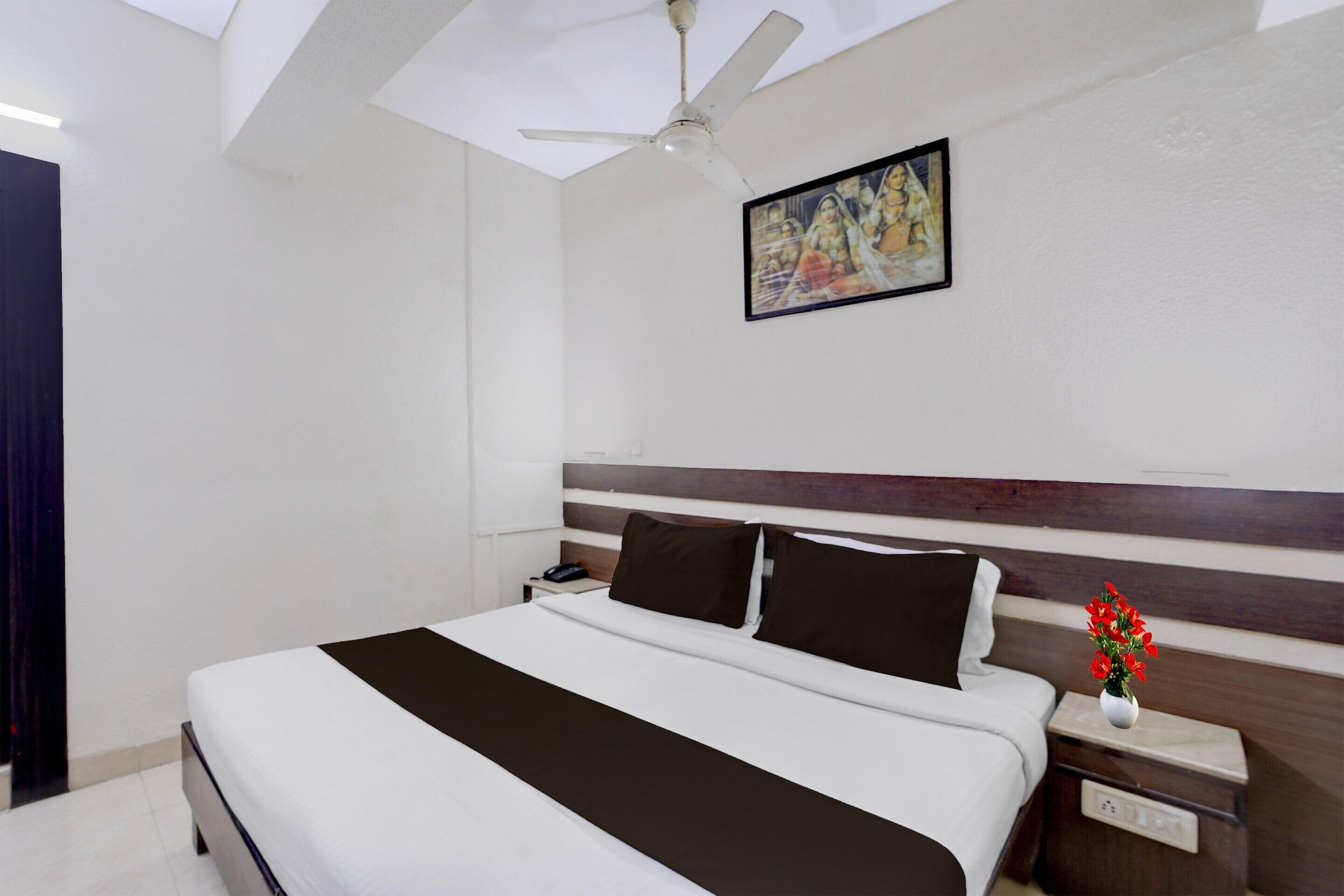 A hotel room with a bed, a nightstand, a wall-mounted picture, and a ceiling fan.