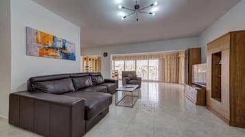Amplia sala de estar con un sofá de cuero marrón, una mesa de centro y un mueble para la televisión.