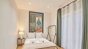 Et pænt opredt soveværelse med et stort plakat, et sengebord med lampe, og en gulvlampe.