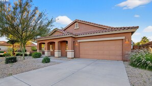 A residential house with a garage, a driveway, and a landscaped front yard. - Luxury Hot Tub Getaway in Estrella Mountain Ranch (Goodyear)
