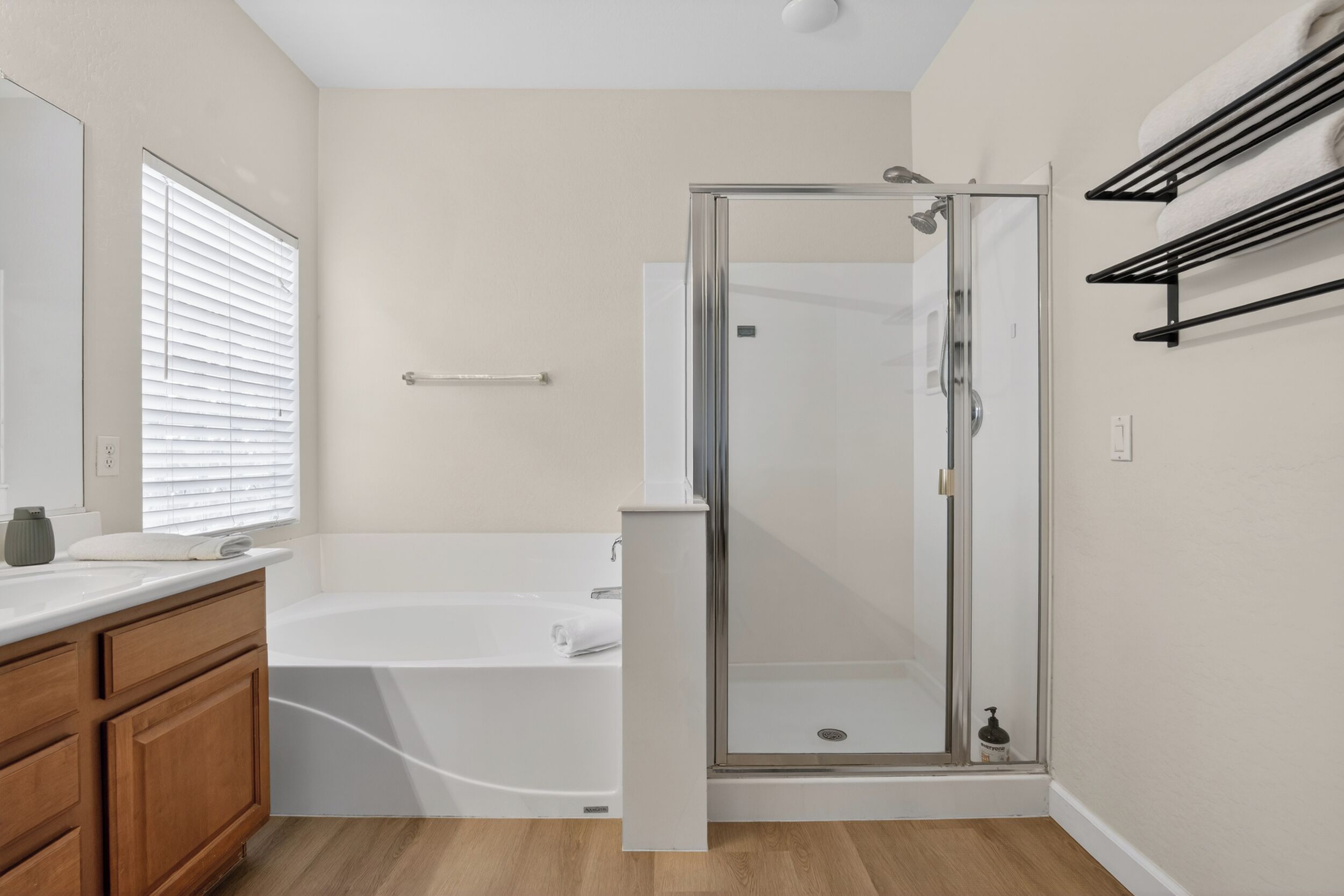 Een moderne badkamer met een douchecabine van glas, een witte badkuip, houten kastjes en een handdoekhouder.