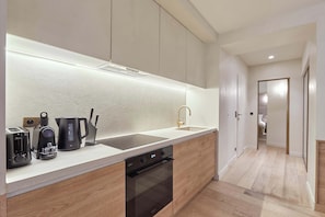 A modern kitchen with a built-in oven, a sink, and a coffee maker. - Exceptional Grand Apartment - Louvre Museum (Paris)