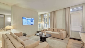A modern living room with a sofa set, a coffee table, and a flat-screen TV mounted on the wall. - Exceptional Grand Apartment - Louvre Museum (Paris)