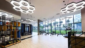 Un gimnasio amplio con luminarias modernas y ventanas grandes que ofrecen vistas a zonas verdes.