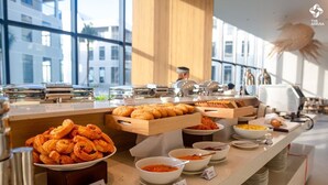 Un bufé con diversas opciones de comida y un cocinero al fondo.
