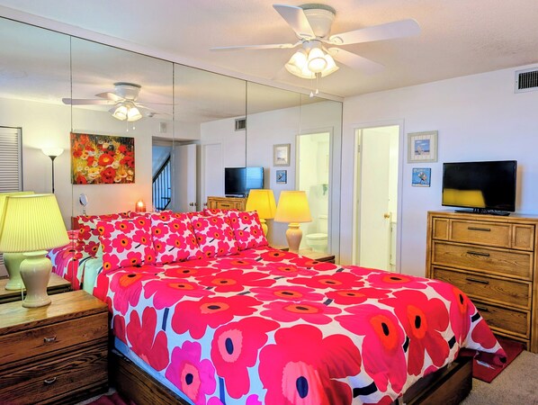 A bedroom with a bed, bedside lamps, a TV, a dresser, and a ceiling fan. - 908 Dover - Sea Colony East (Bethany Beach)