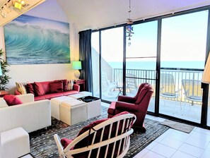 A modern living room with a large ocean view, a red sofa, white armchairs, and a red armchair. - 908 Dover - Sea Colony East (Bethany Beach)