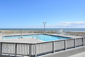 Ein Pool mit Holzterrasse und Blick auf den Strand.