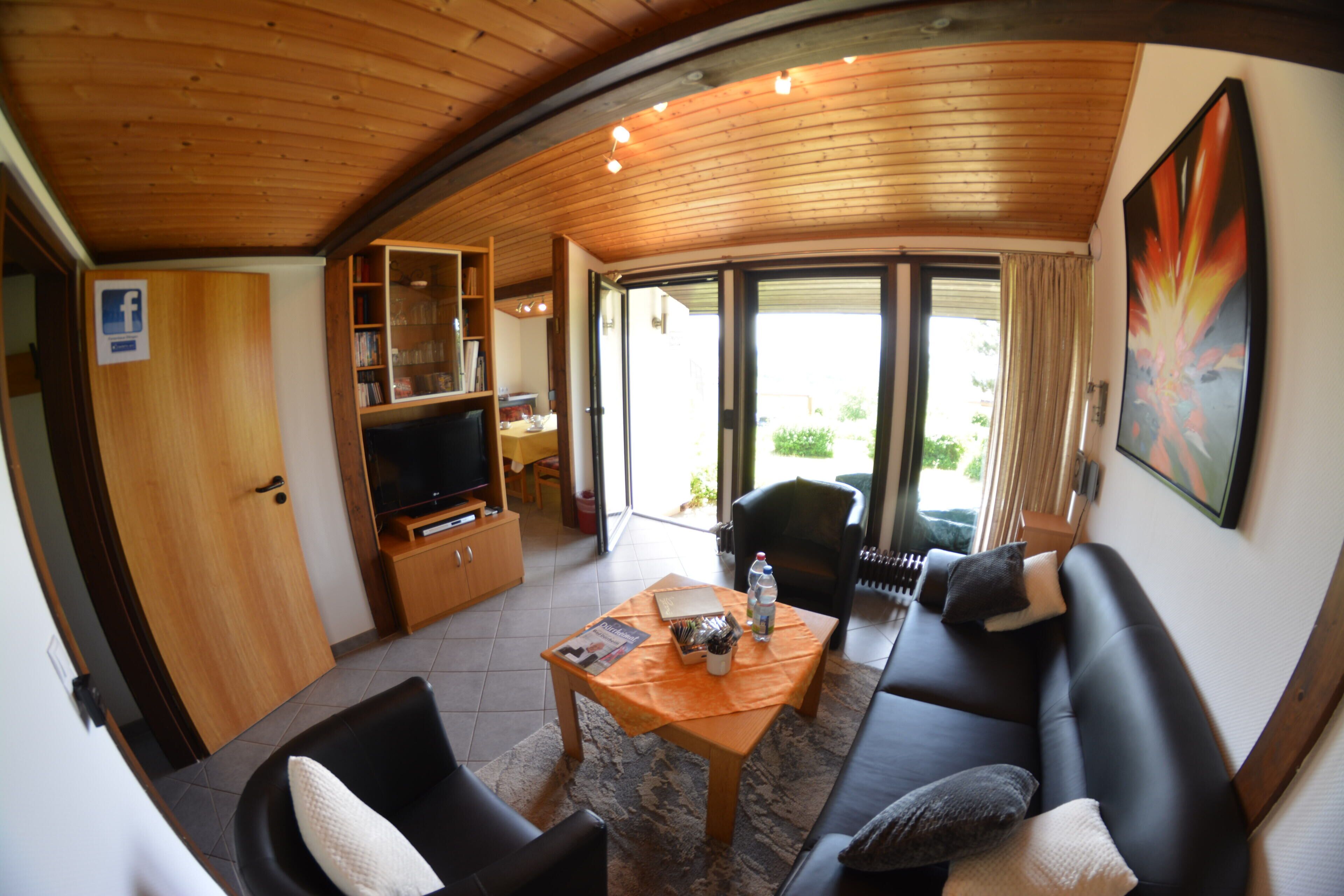 A living room with a sofa, a coffee table, a television, and a bookshelf.