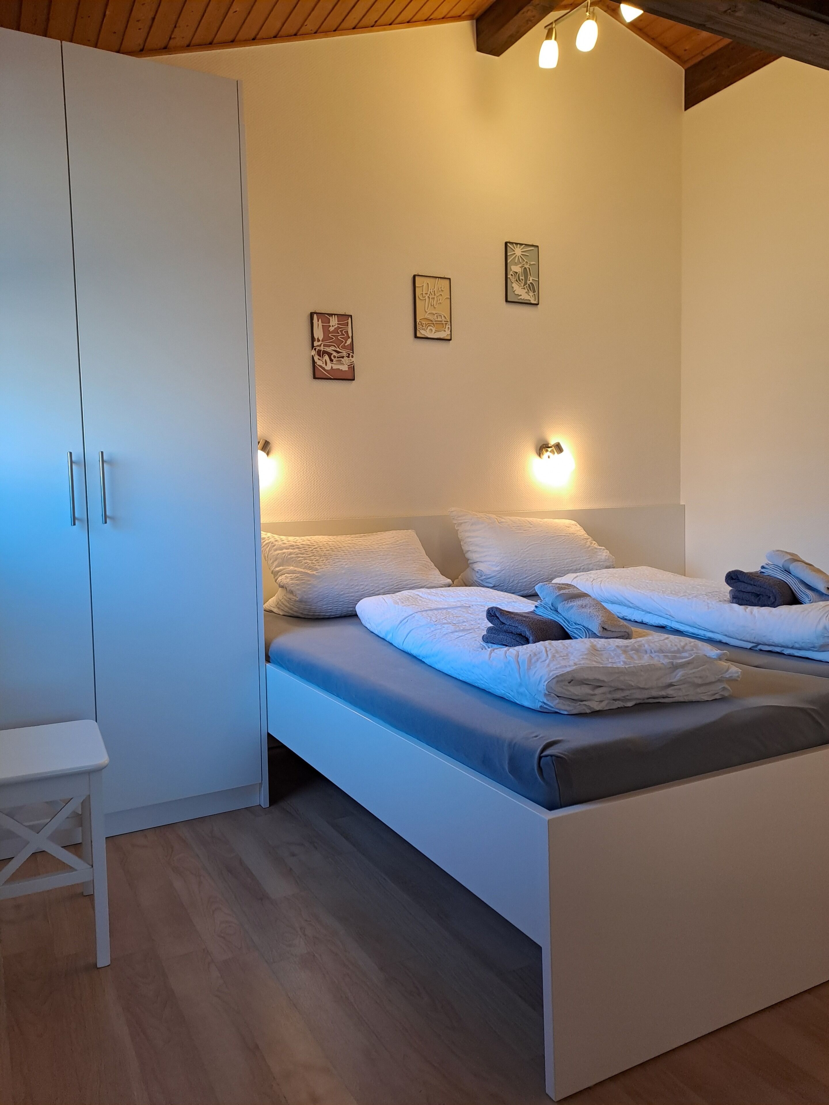 Ein Schlafzimmer mit einem Bett, einem weißen Kleiderschrank und Wandleuchten.