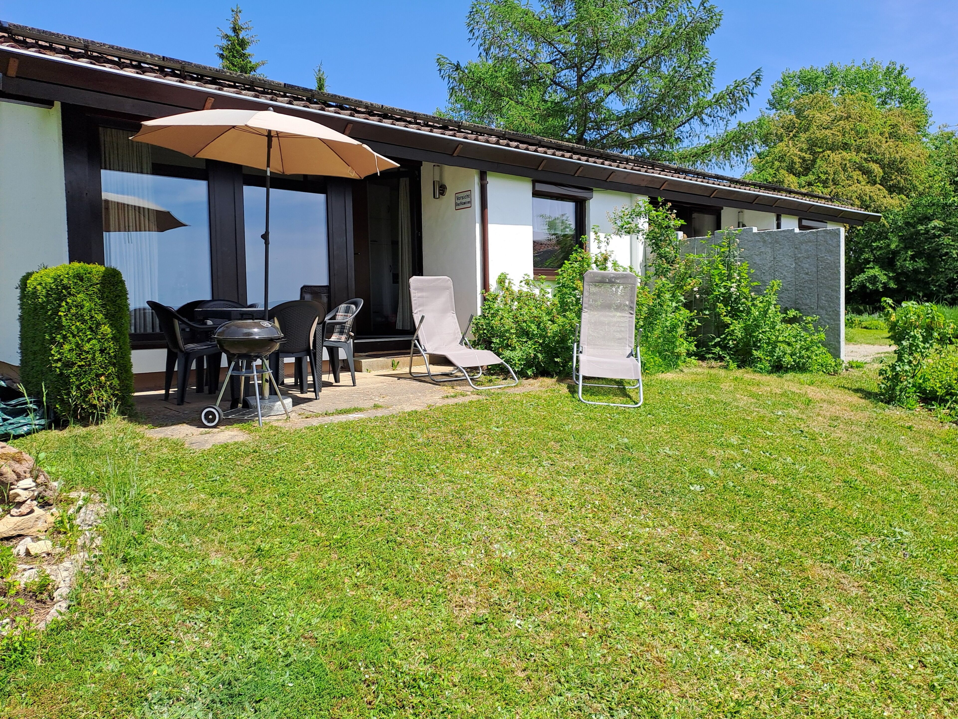 A patio area with outdoor furniture, a barbecue grill, and a signboard.