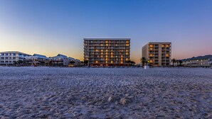 Un hotel sulla spiaggia con diversi edifici, una spiaggia sabbiosa e un cielo sereno.