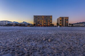 A beachfront hotel with multiple buildings, a sandy beach, and a clear sky. - Seacrest 703 - 1 BR | Gulf Front | Sleeps 5 (Gulf Shores)