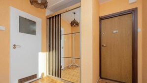 Ein Hotel Eingang mit einer Schiebetür aus Glas, einer Holztür, einer Fußmatte und einer Deckenleuchte.