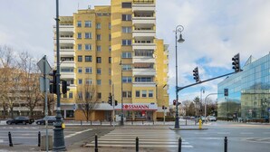 Ein mehrstöckiges gelbes Gebäude mit einer sichtbaren Ladenfläche, auf der Straßenebene das Schild "ROSSMANN" zu sehen ist.