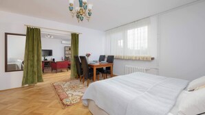 Ein Schlafzimmer mit einem großen Bett, einem Schreibtisch mit Stühlen, einem Spiegel und einer Chandelüster.