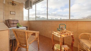 Ein Balkon mit Korbmöbeln, einem kleinen Tisch mit Pflanze und einem Ziertisch mit Teekanne.