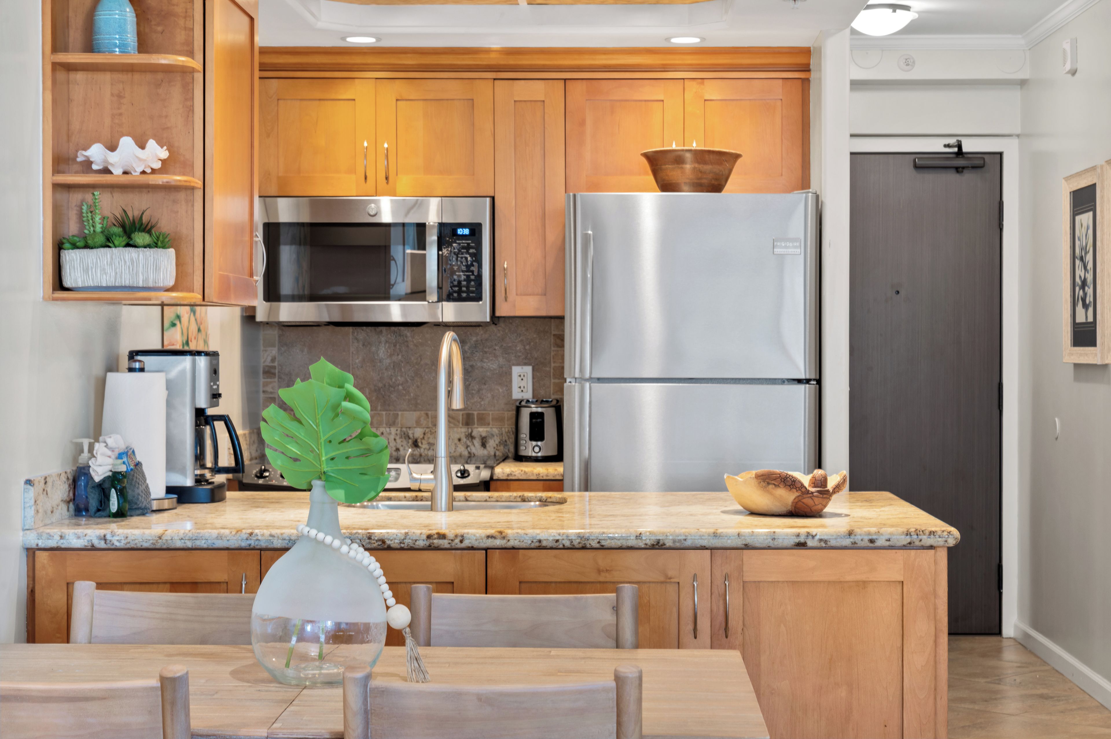 A modern kitchen with wooden cabinets, stainless steel appliances, and a granite countertop.