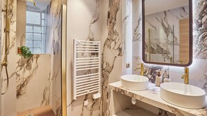 A bathroom with marble walls, a white towel rack, two sinks, and a large mirror. - Suite AC Saint Germain des Pres-rue de Rennes (Paris)