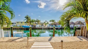 Un puerto deportivo con barcos amarrados, un sendero que lleva al agua y palmeras.