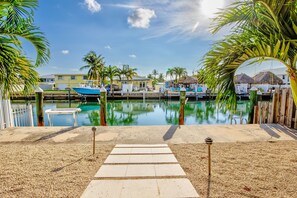 A marina with boats docked, a pathway leading to the water, and palm trees. - Trip Around the Sun 2/2 + dockage & Cabana Club (Key Colony Beach)