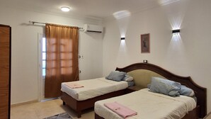 A bedroom with two beds, a bathroom, and a door. - El Agamy Hotel Apartment (Luxor)