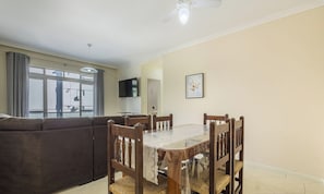 A living room with a sofa, a dining table with chairs, a ceiling fan, and a window with curtains. - 2 Bdrm apt 250m From the Beach in Center Sdc0601 (Balneário Camboriú)