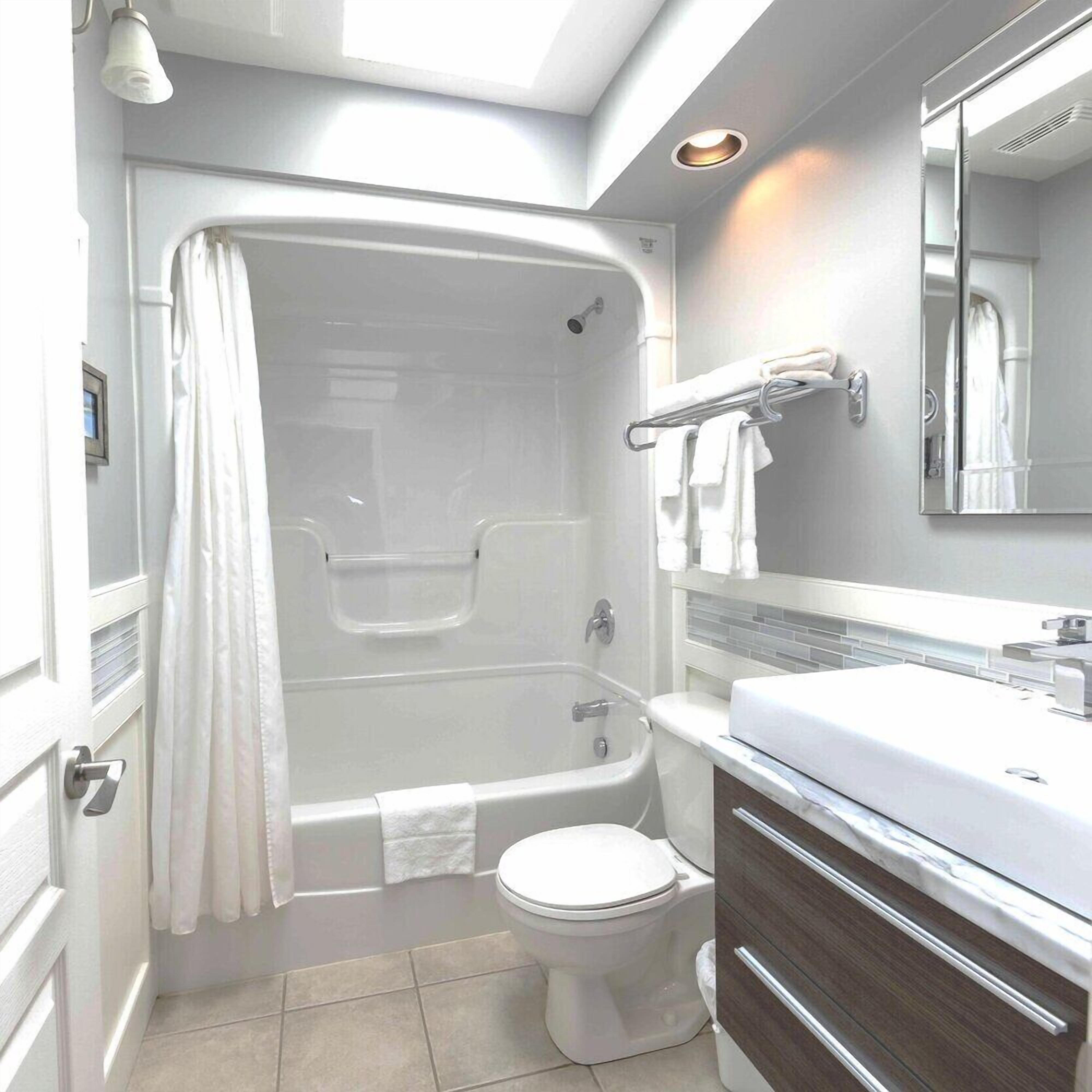 A modern bathroom with a bathtub, toilet, vanity, and a shower area.