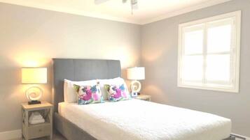 A bedroom with a bed, two bedside tables, a ceiling fan, and a window.