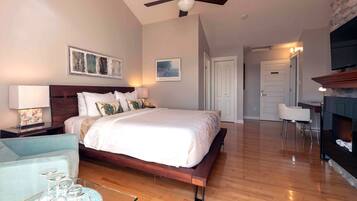 Un dormitorio con cama de madera, una mesita de noche con lámpara, una silla y una chimenea.