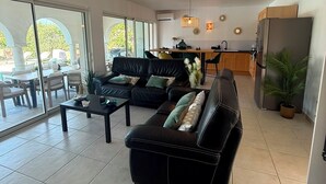 Ein geräumiger Wohnbereich mit einer Couch, einem Couchtisch und einem Essbereich mit Stühlen und Tisch.