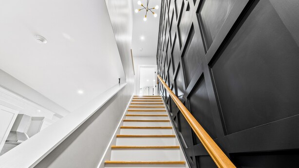 A modern staircase with wooden steps and a black wall with geometric patterns.