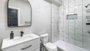 A modern bathroom with a white vanity, a toilet, and a bathtub.
