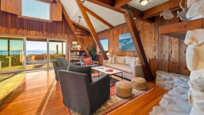 A spacious room with wooden beams, large windows, a cozy seating area, and a view of the ocean. - 25% Off Sept 7-9, On The Sand Perfect 4 Families! (Ventura)