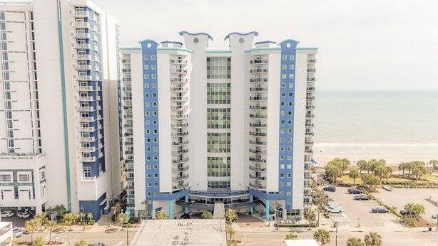 Ett hotell med flera våningar, balkonger, en central innergård och utsikt över stranden.