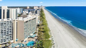 Ein Hochhotel mit mehreren Etagen, einem Schwimmbad und einer Lage am Strand.