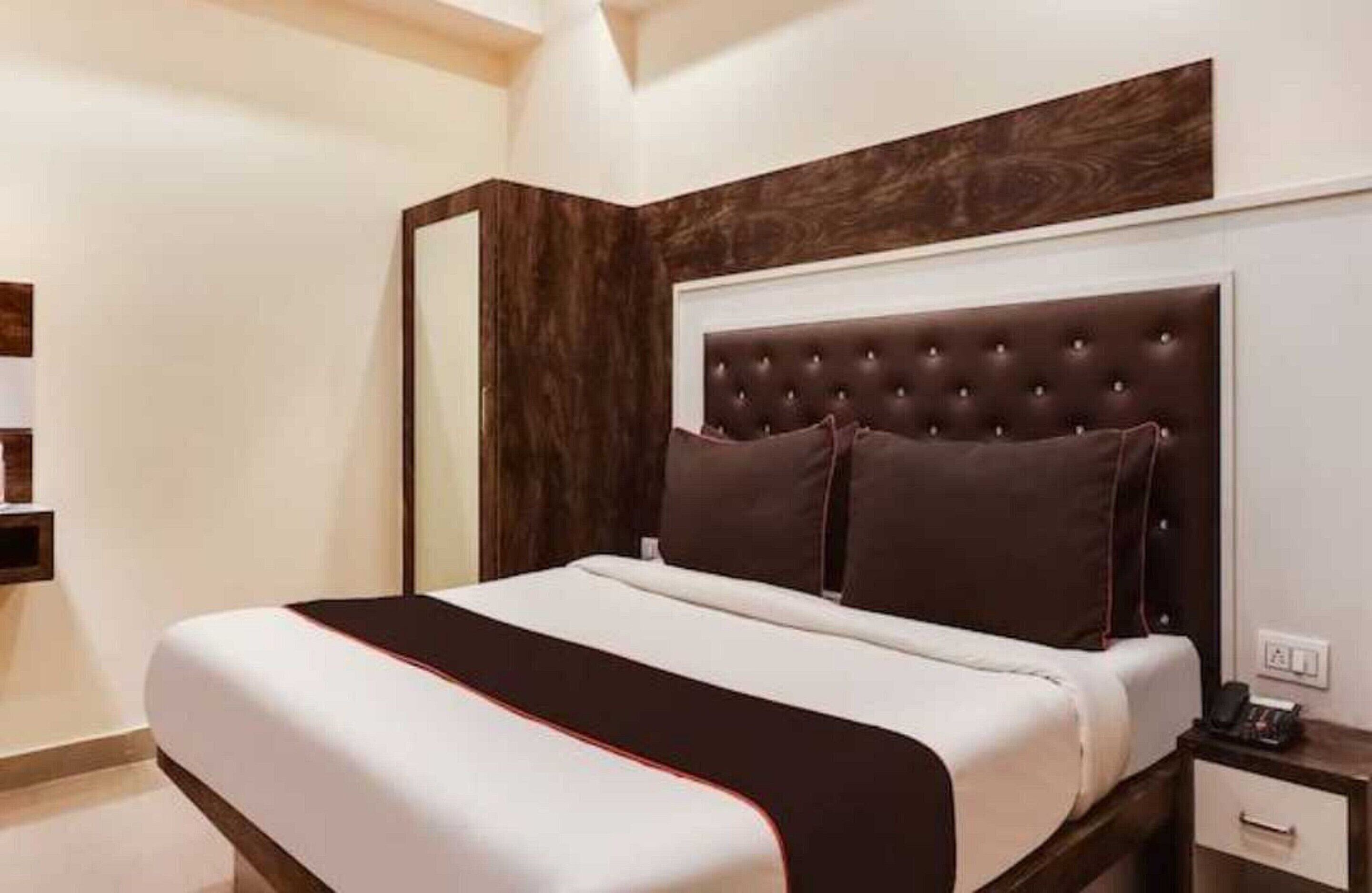 A neatly made bed with a dark headboard and white bedding.
