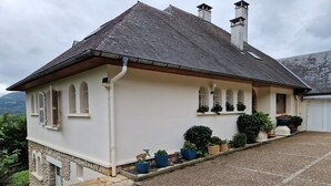 A two-story house with a sloped roof, multiple chimneys, and a gravel driveway. - guest room overlooking the town of Lourdes and splendid view of the Pyrenees (Lourdes)
