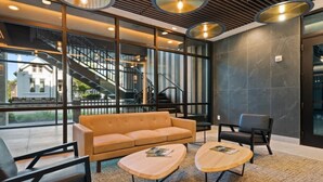 A modern lobby with a sofa, two coffee tables, and a staircase. - Music Row Bliss • Pool, Rooftop + Free Parking (Nashville)