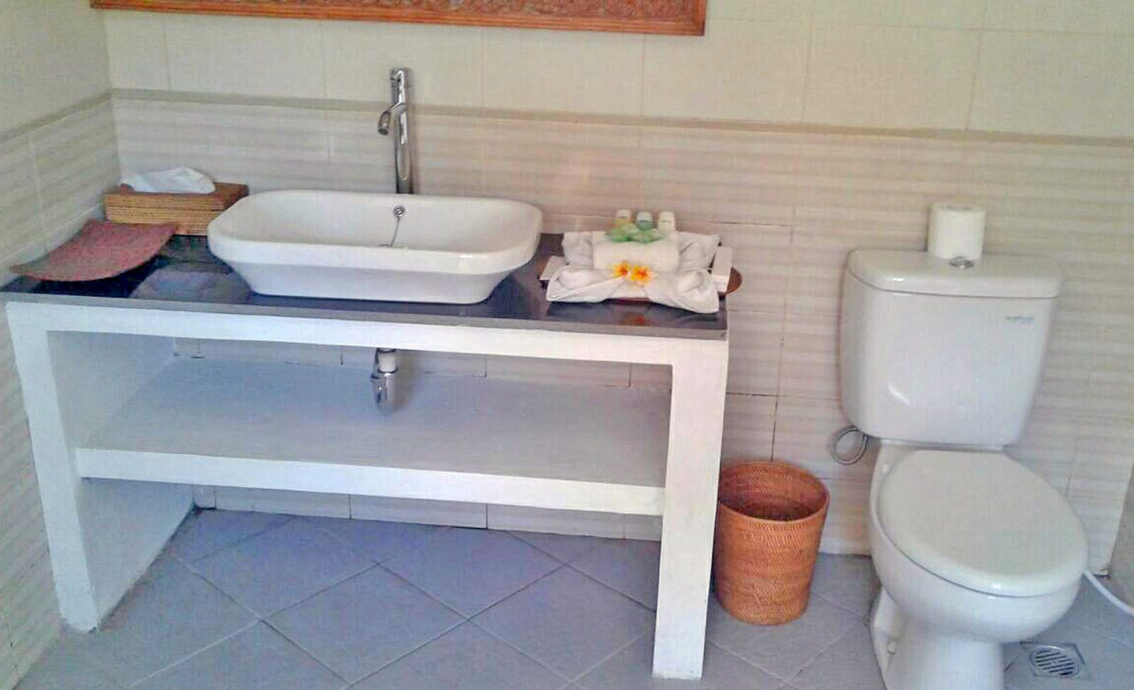 A bathroom with a white sink, a toilet, and a small wicker basket.