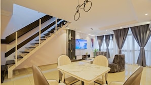 Una sala de estar moderna con una escalera, un comedor con una mesa de mármol y un televisor de pantalla plana.