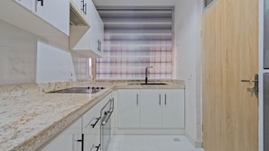 Una cocina moderna con armarios blancos, encimera de granito y pileta integrada.