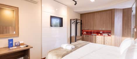 A hotel room with a bed, a desk, a TV, a mirror, and a wardrobe.